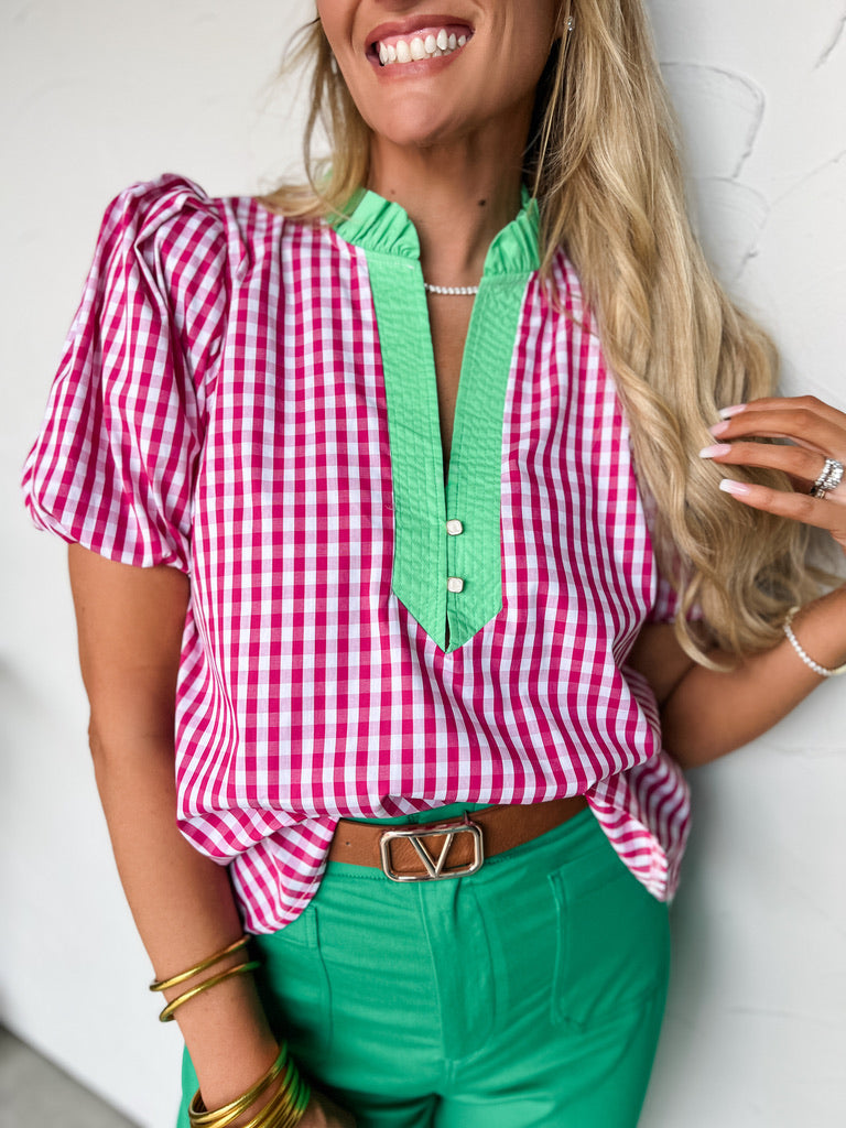 Woman wearing a pink and green checkered blouse with a white background