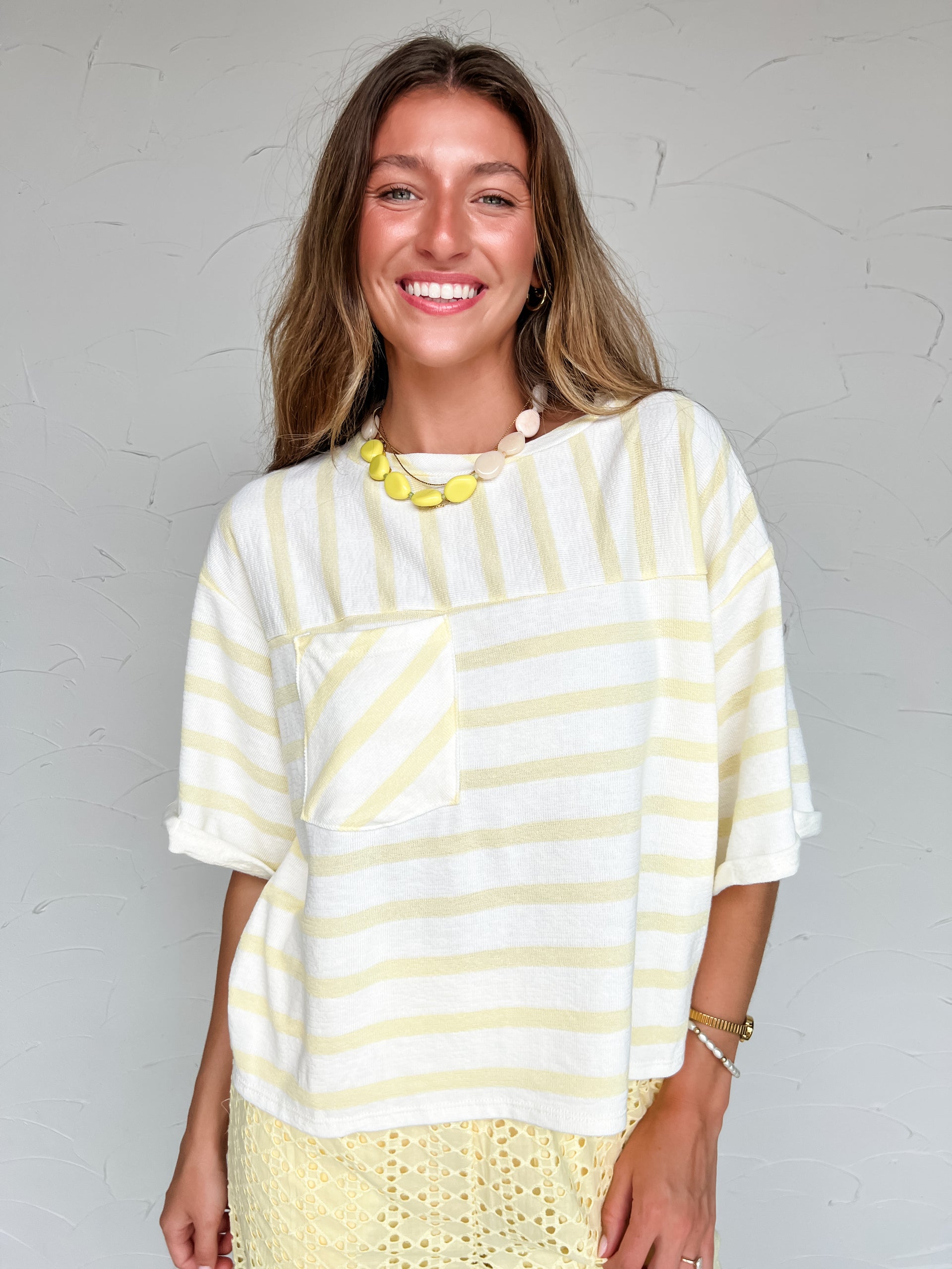 Woman wearing a white and yellow striped top with a plain background
