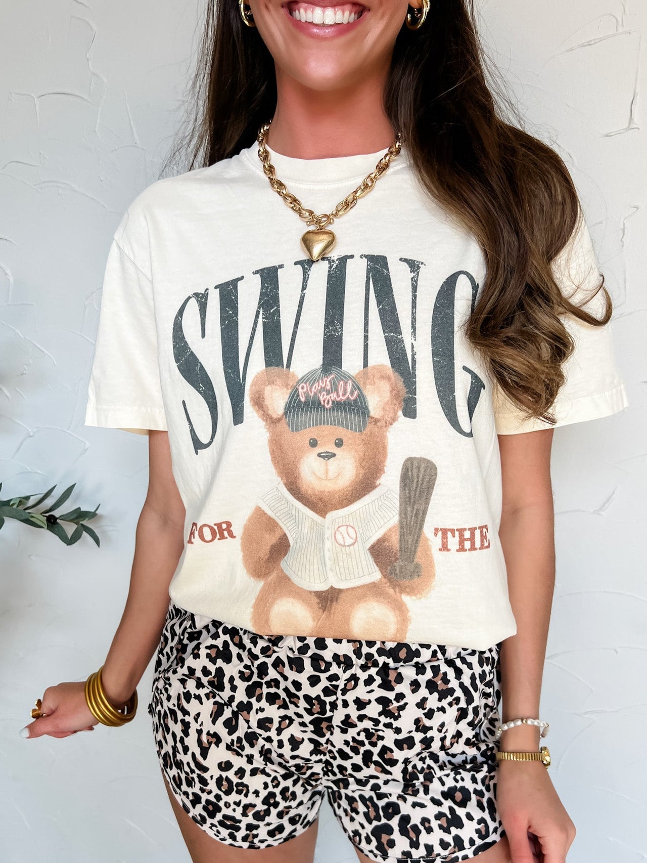 Woman wearing a graphic t-shirt with a bear and text design, paired with leopard print shorts.