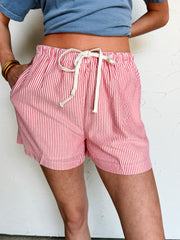 Person wearing red and white striped shorts with a plain background