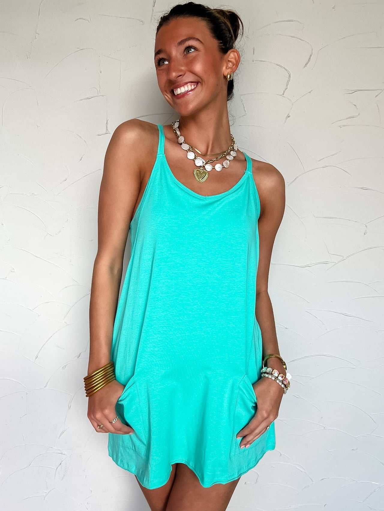 Woman wearing a turquoise dress against a white textured wall