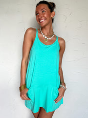Woman wearing a turquoise dress against a white textured wall