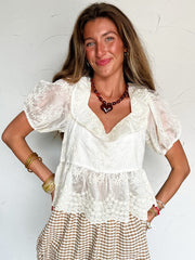 Woman wearing a white lace top and checkered skirt against a white background