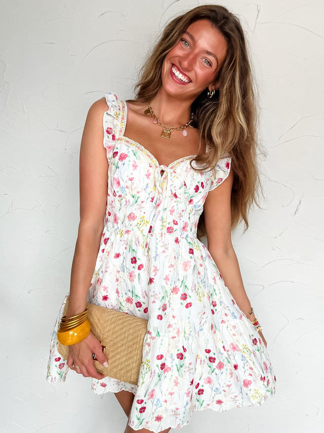 Woman wearing a white floral dress against a white wall