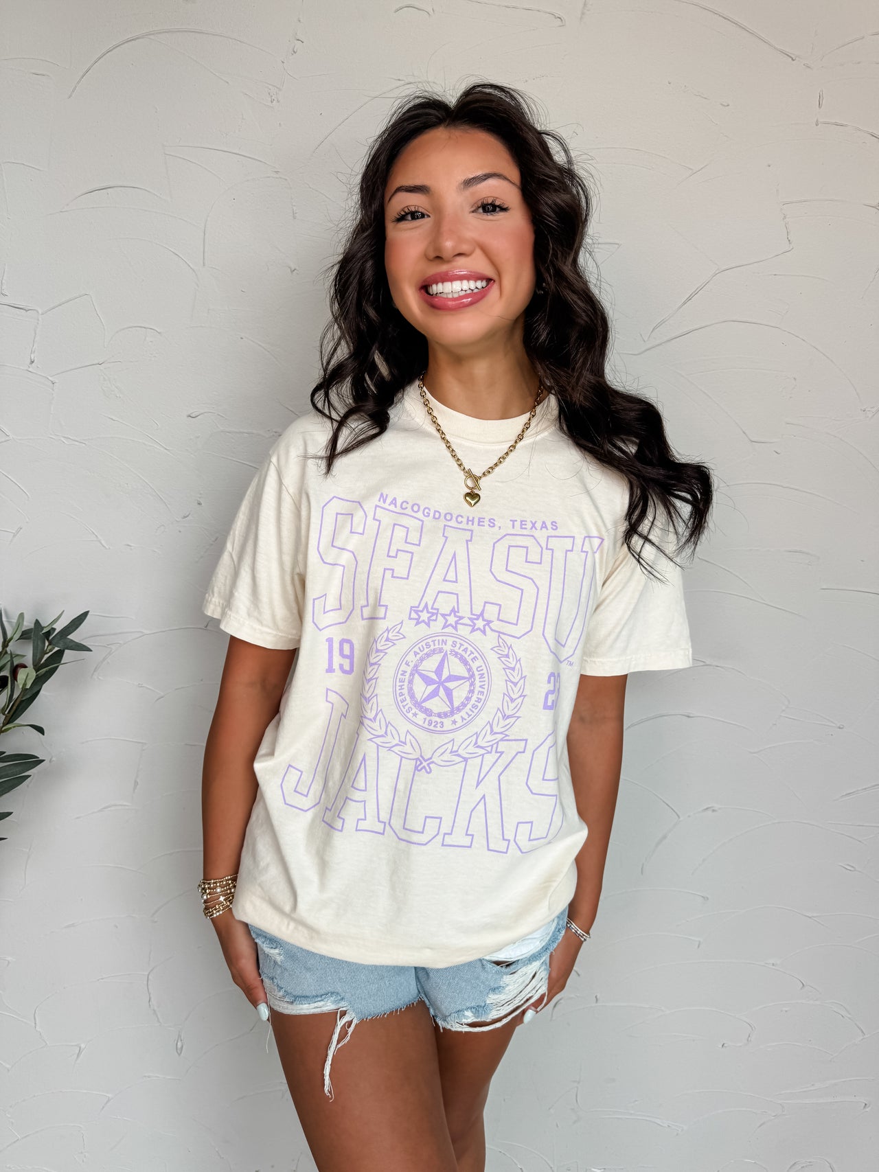 Woman wearing a white t-shirt with purple text against a light gray wall