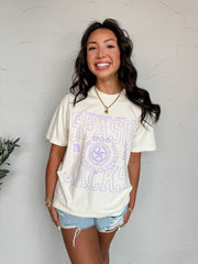 Woman wearing a white t-shirt with purple text against a light gray wall
