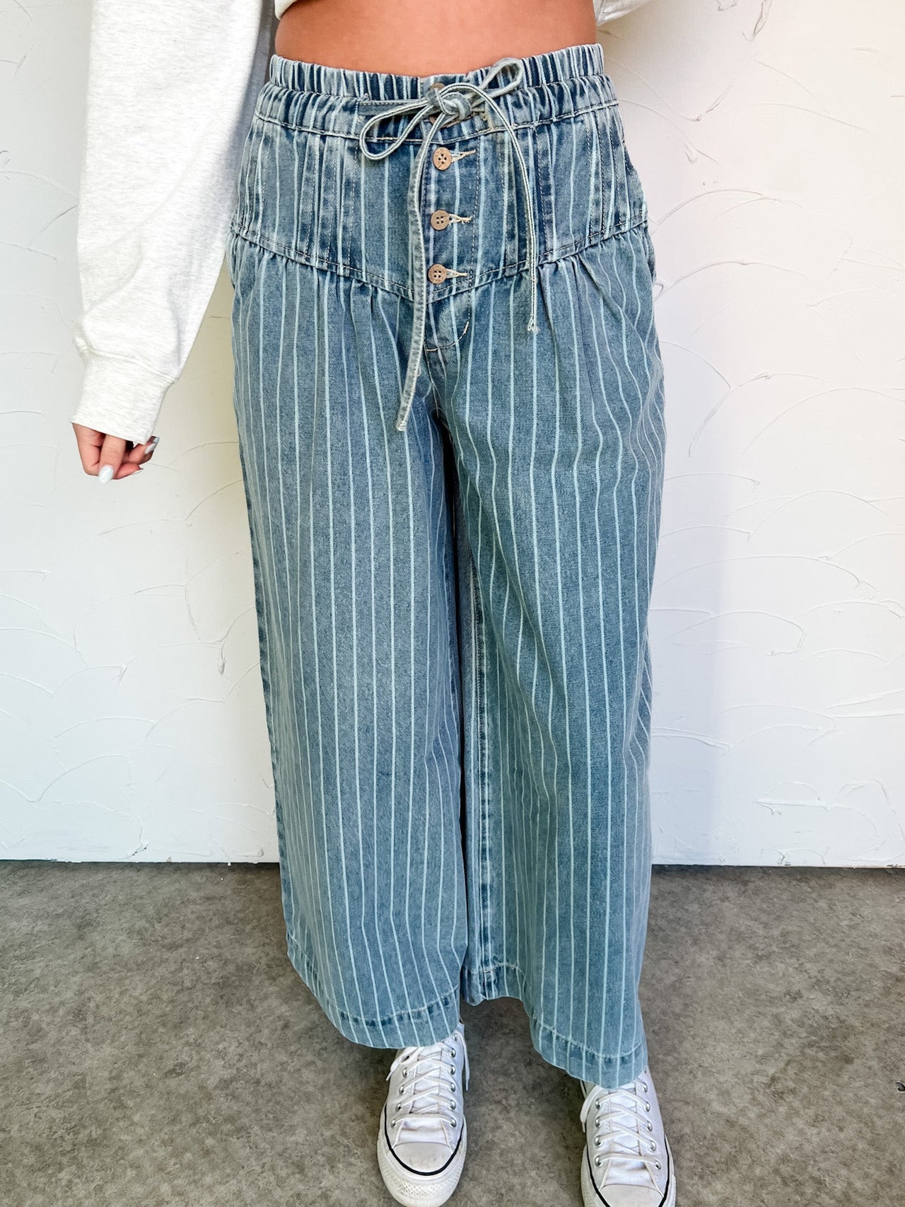 Person wearing blue striped denim pants with a draw string waist and on a white background