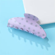 Purple hair clip with gray polka dots on a light blue background