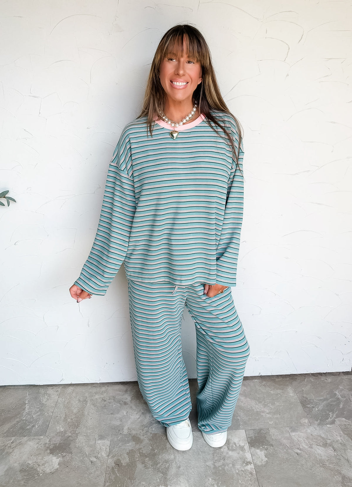 Lesly modeling the Anniewear In My Element Brushed Stripe Pants Set in size Large, made from 92% polyester and 8% spandex, featuring green horizontal stripes with light and dark accents, a round-neck long-sleeve top with dropped shoulders, and matching full-length wide-leg pants with a gathered drawstring waist.
