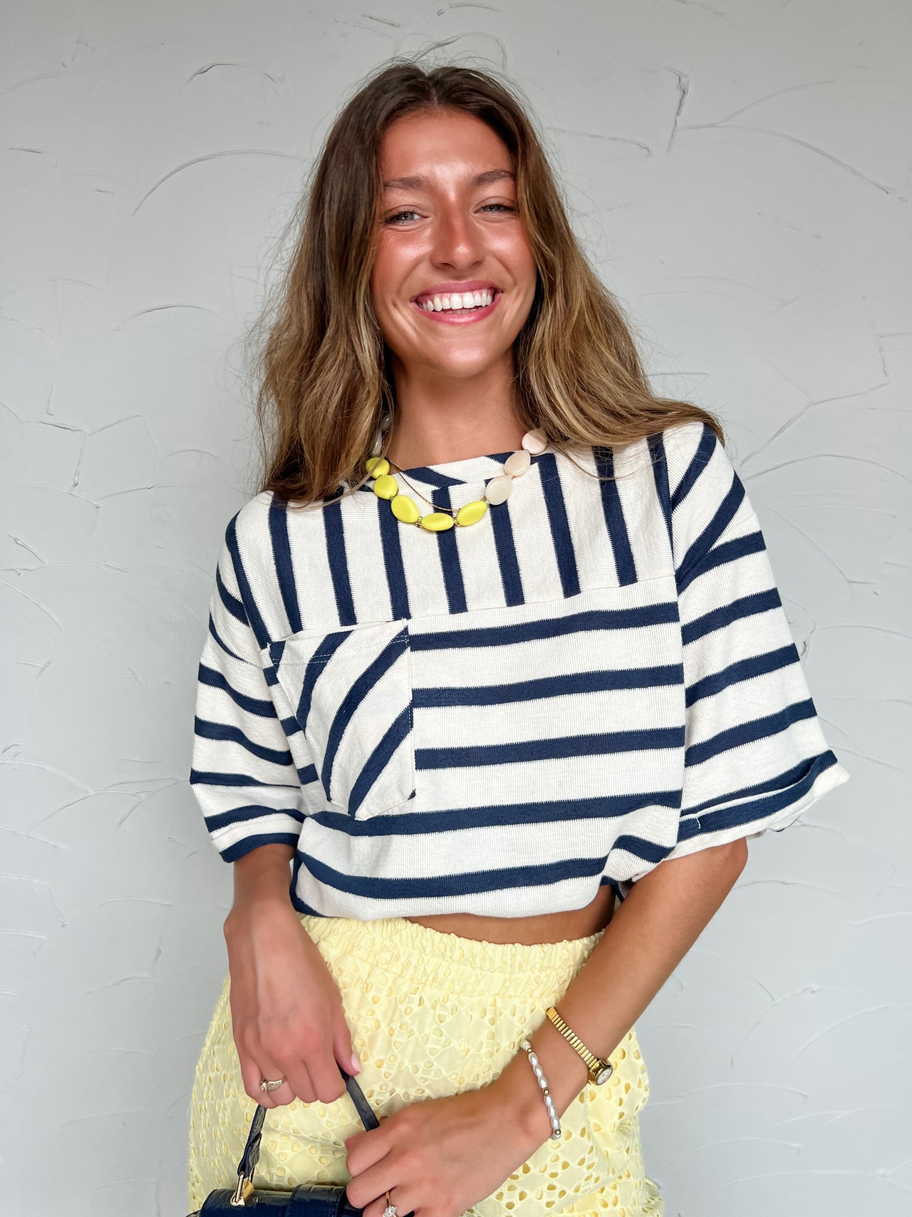 Woman wearing a striped shirt and yellow skirt against a light gray background