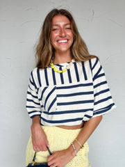 Woman wearing a striped shirt and yellow skirt against a light gray background