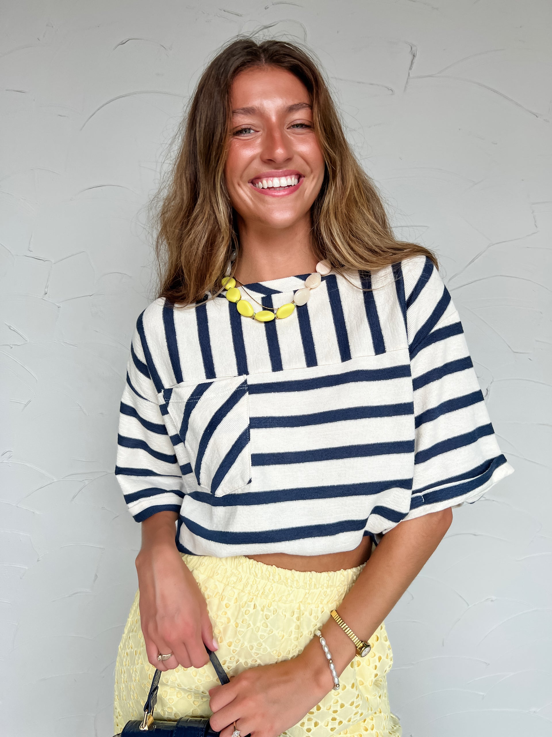 Woman wearing a striped shirt and yellow skirt against a light gray background