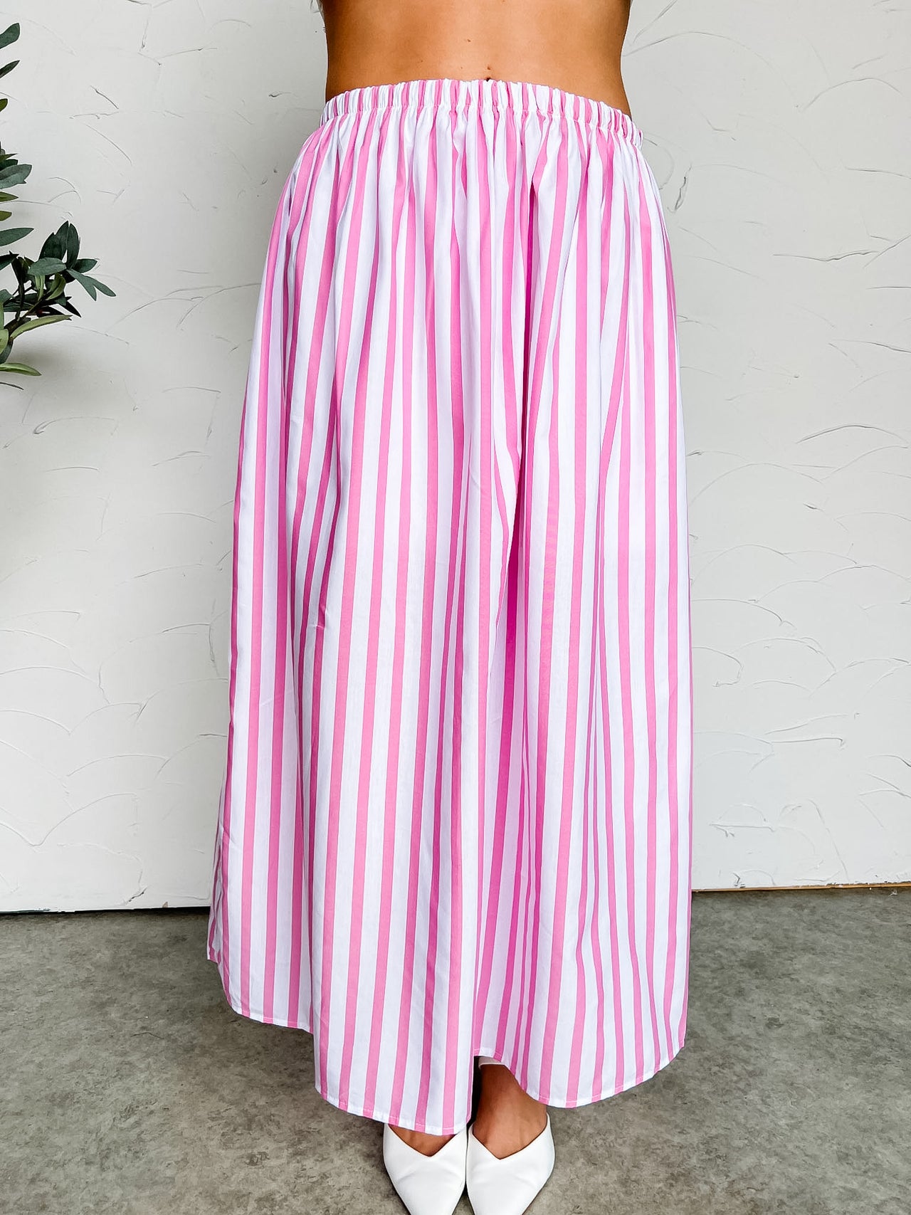 Pink and white striped skirt worn by a person against a white background