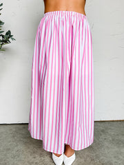 Pink and white striped skirt worn by a person against a white background
