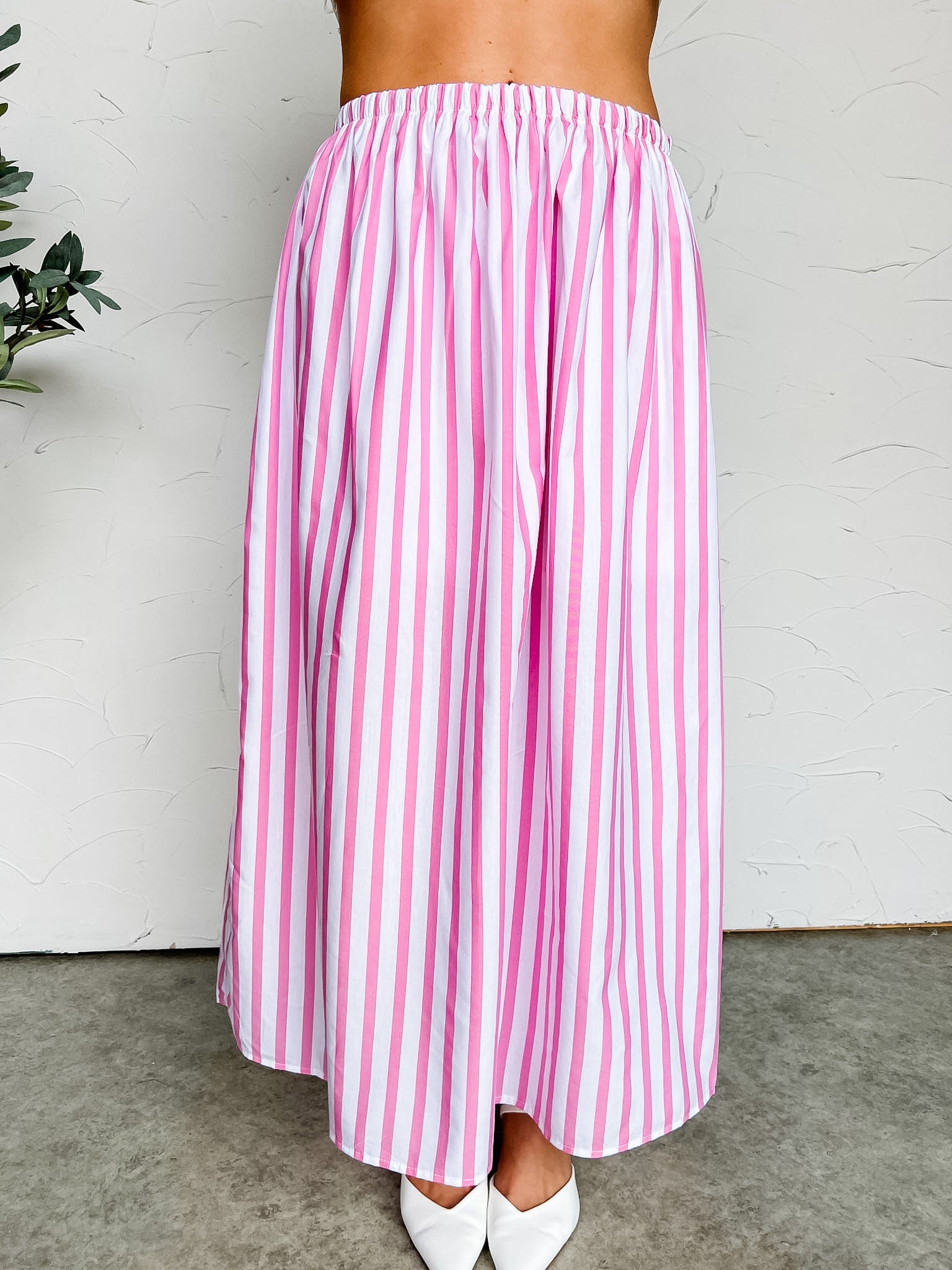 Pink and white striped skirt worn by a person against a white background