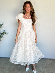 Woman wearing a white lace dress against a plain background