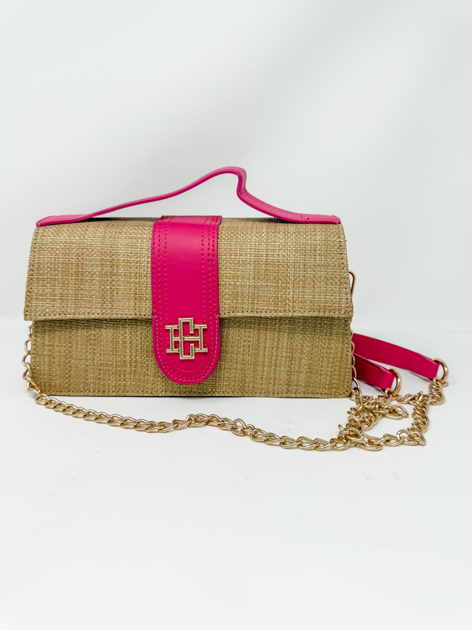 Woven handbag with pink strap and gold chain on a white background