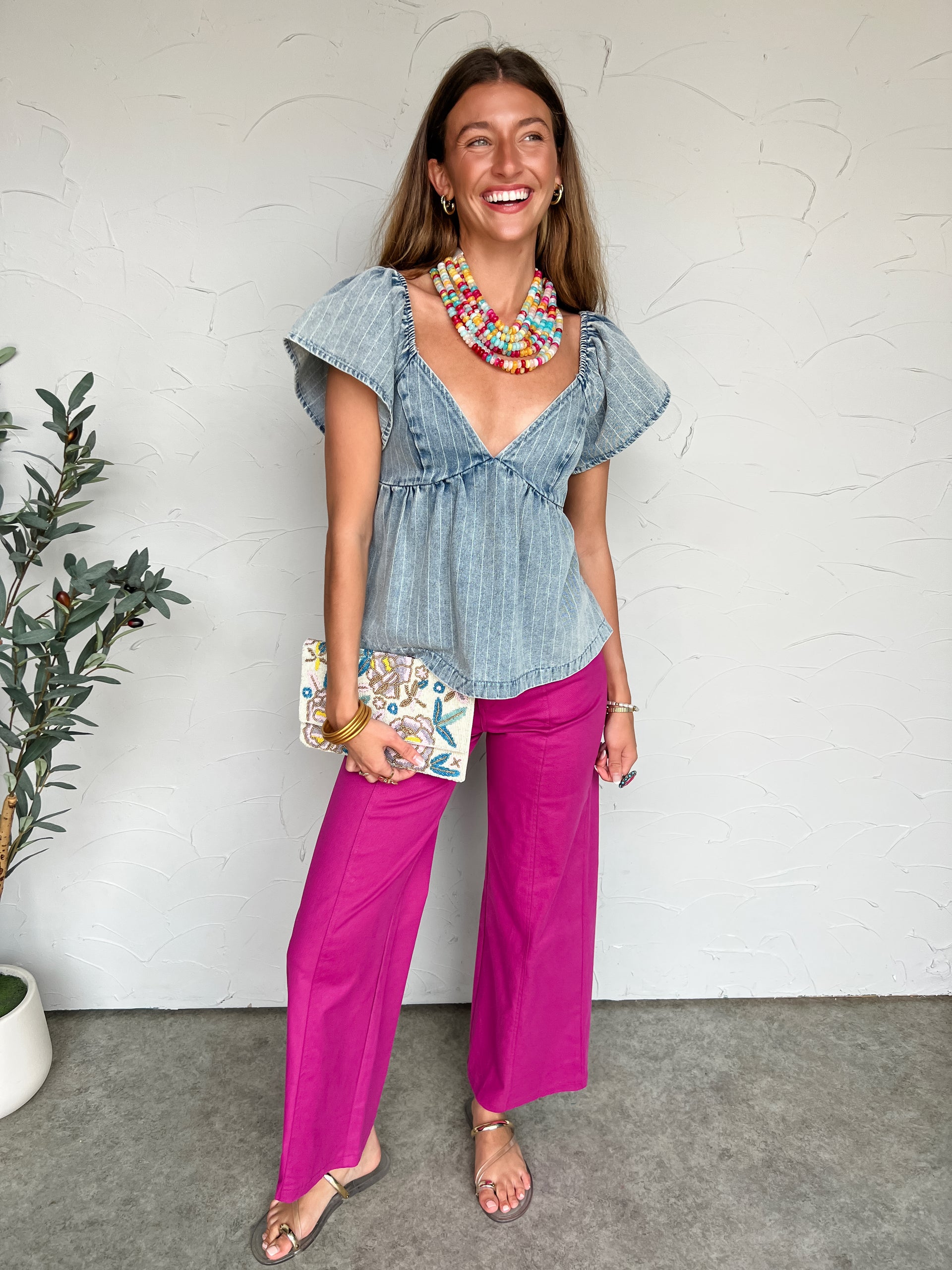 Woman wearing a denim top and pink pants with a white background