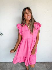 Lesly modeling the Umgee Never Waste A Moment Double Sleeve Dress in Peony, size Large, made from 100% polyester with textured pink fabric, double-layer ruffle sleeves, a split neckline with stand collar, and a gathered tiered skirt with a ruffled hem, styled with a layered pearl and heart necklace, gold-tone bracelets, and patterned ankle boots.