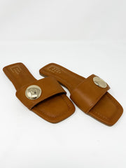 Pair of brown sandals with a gold round detail on strap on a white background