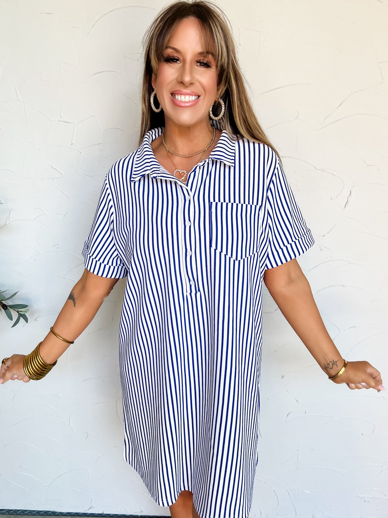 Woman wearing a blue and white striped t-shirt dress against a white background