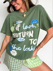 Woman wearing a green t-shirt with text and graphics, plaid shorts, and a camouflage cap.