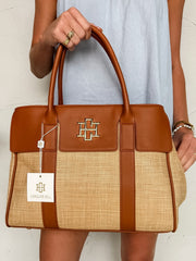 Person holding a brown and beige handbag with a visible brand logo against a white background