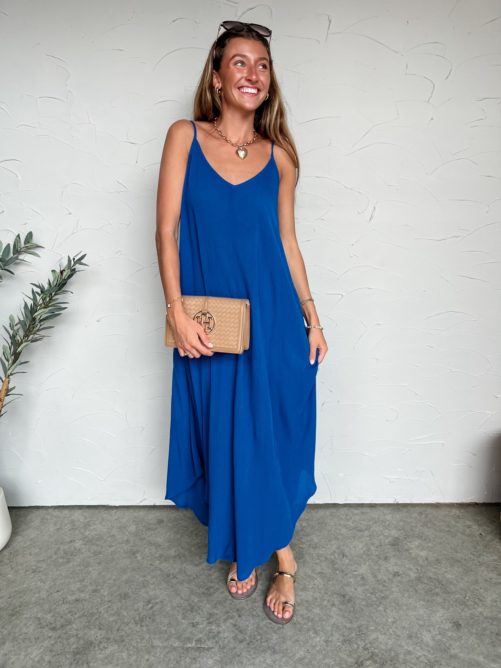 Girl in long blue dress in front of plain wall 