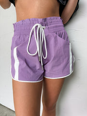 Purple shorts with white drawstring and trim on a neutral background