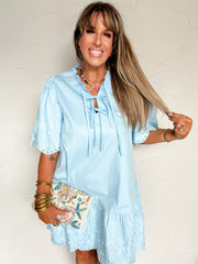 Woman wearing a light blue dress against a white wall