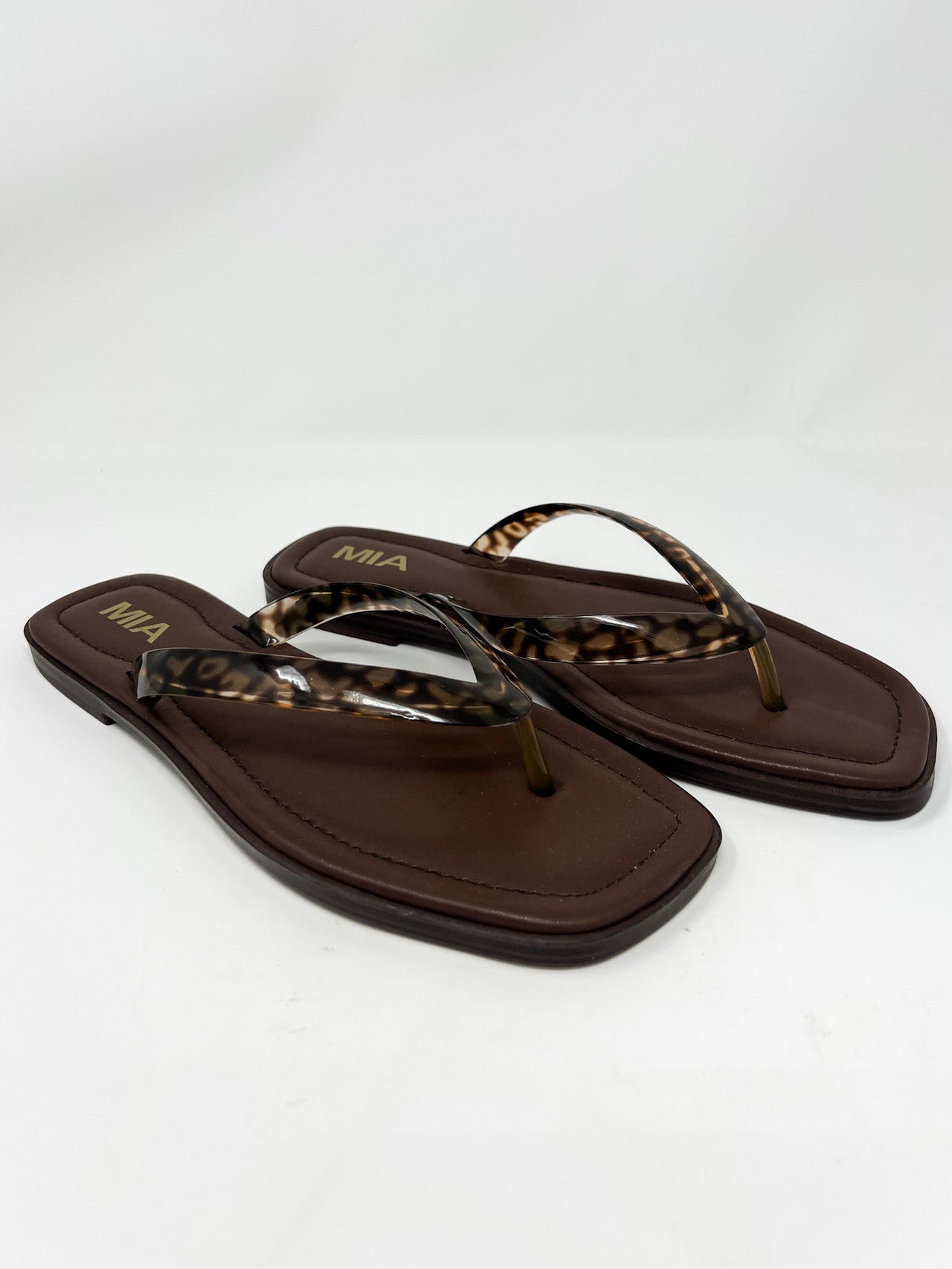 Pair of brown sandals with leopard print straps on a white background