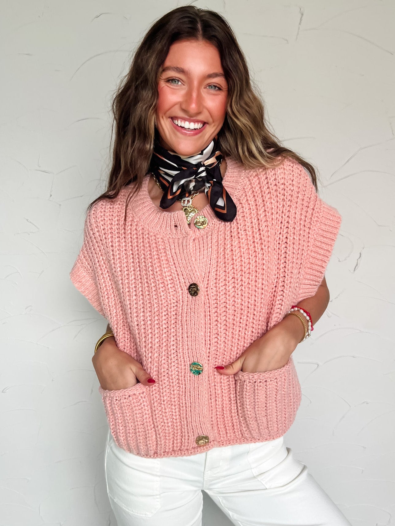 Woman wearing a pink knitted vest with a white background