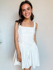 Woman wearing a white dress against a plain background
