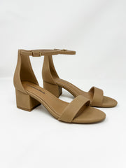 A pair of City Classified brand block heel sandals in a warm nude tan color, shown against a solid white background. The shoes feature a single toe strap, an adjustable ankle strap with a small gold buckle, a high closed back, and a low, chunky block heel.