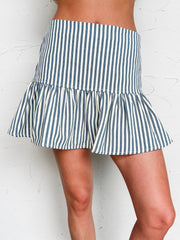 Person wearing a navy and white striped skirt against a white wall.