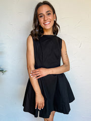 Woman wearing a black dress against a white wall