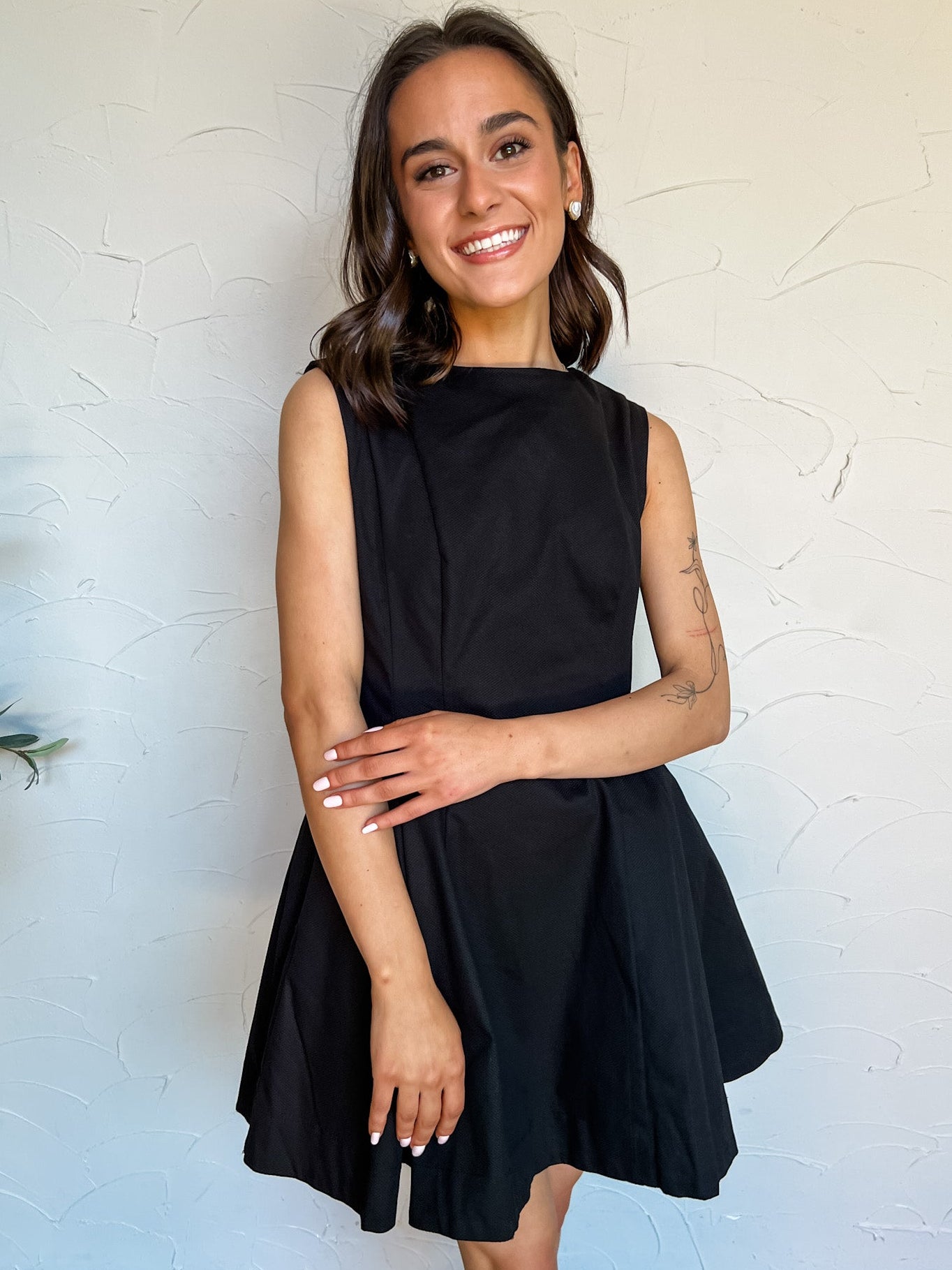 Woman wearing a black dress against a white wall