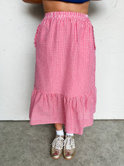 Person wearing a red and white checkered midi skirt with a plain background