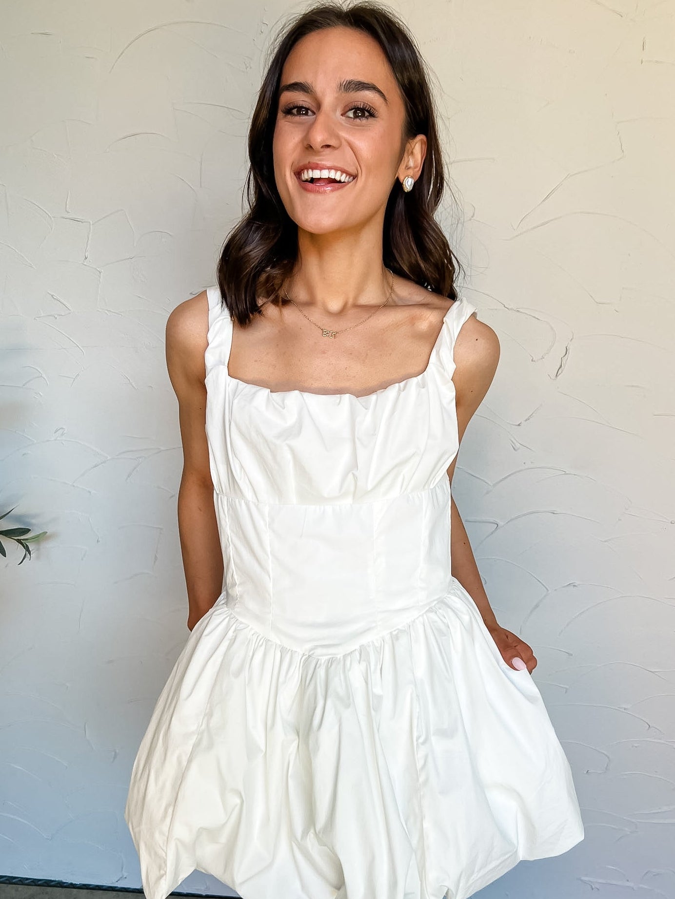Woman wearing a white dress against a plain background