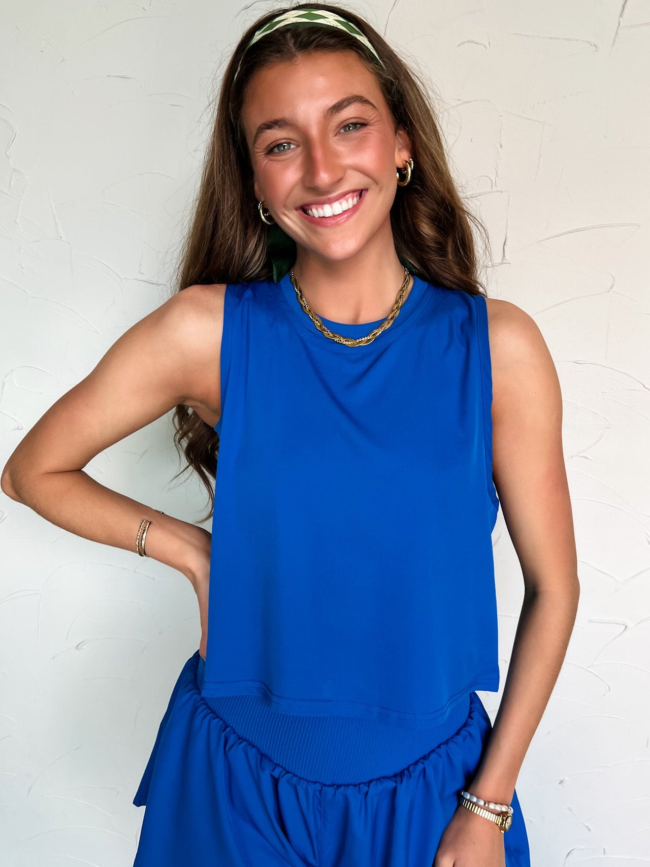 Woman wearing a blue sleeveless top and blue shorts against a white background