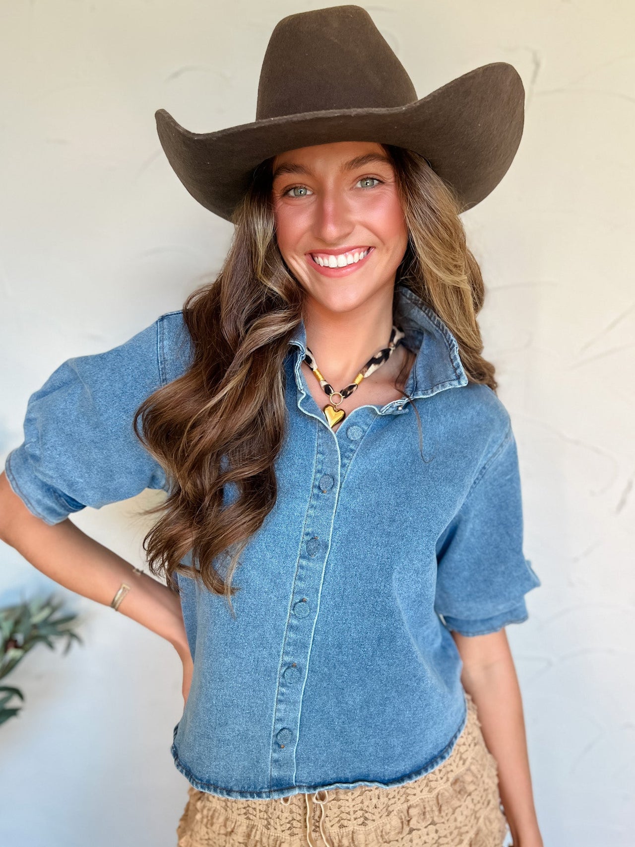 Woman wearing a denim shirt and cowboy hat against a white background
