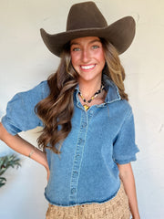 Woman wearing a denim shirt and cowboy hat against a white background