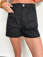 Black polka dot shorts worn by a person on a light background