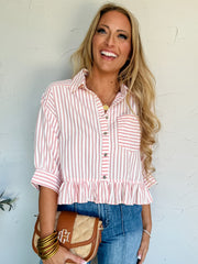 Woman wearing a pink and white striped shirt with blue jeans, holding a brown handbag against a light background.