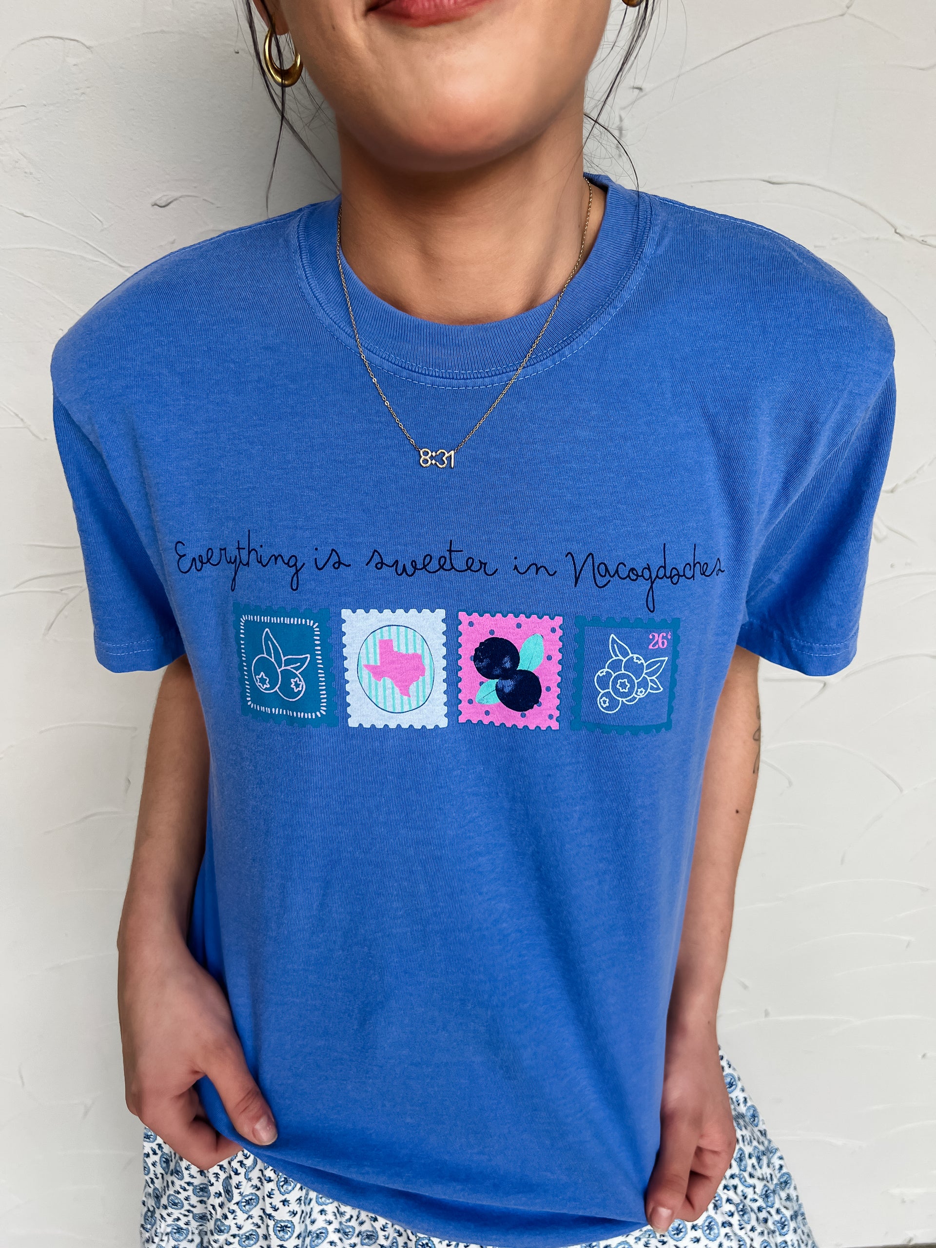 Girl in blueberry festival shirt in front of plain wall 