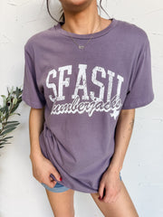Person wearing a purple t-shirt with 'SFASU Summerfakes' text against a white textured wall.