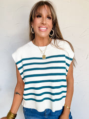 Woman wearing a white and teal striped sleeveless sweater against a light background