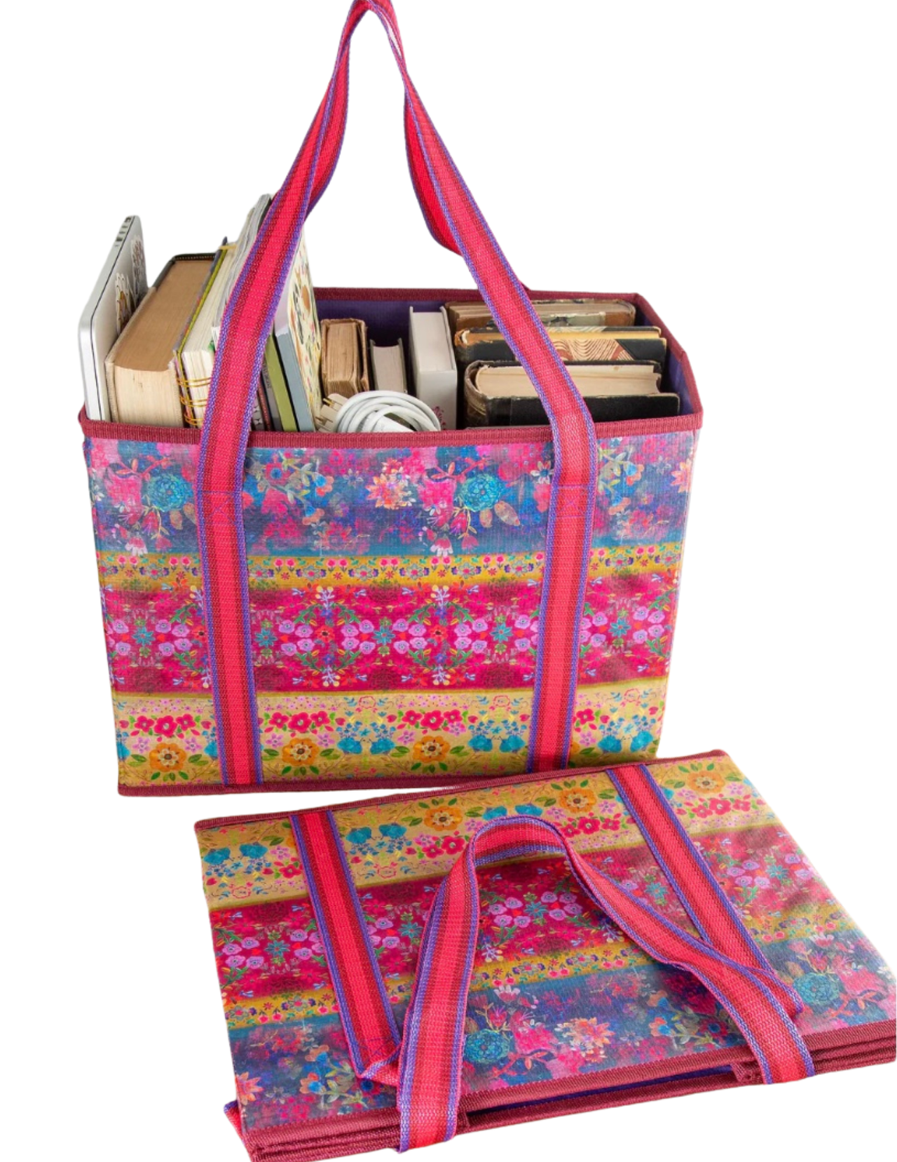 Colorful floral-patterned tote bag with books and items on a white background