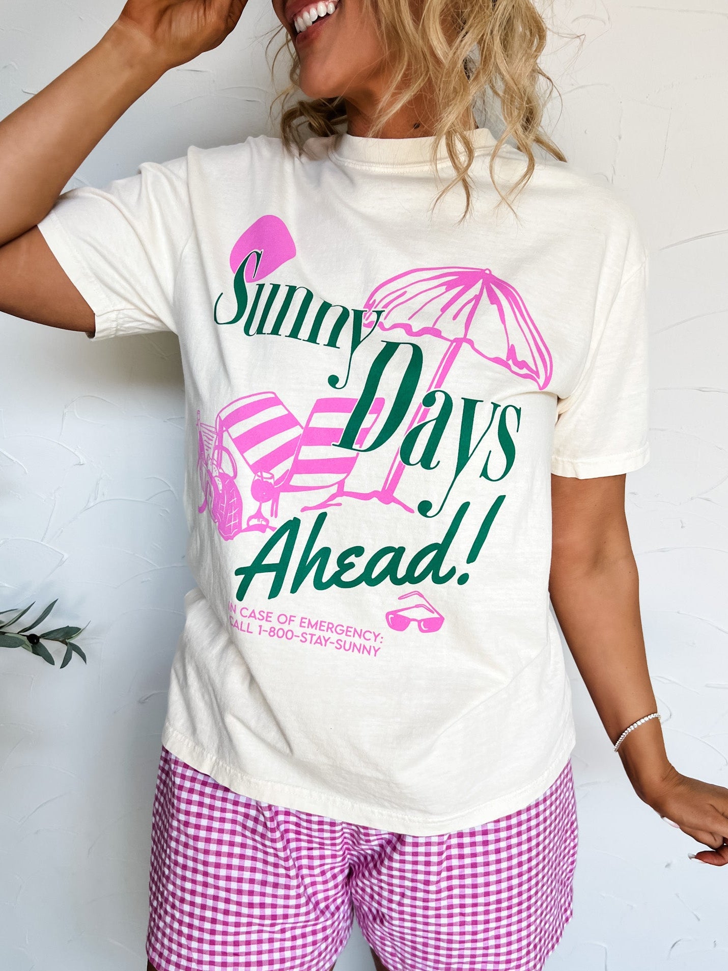 Person wearing a white t-shirt with 'Sunny Days Ahead!' text and pink shorts on a white background
