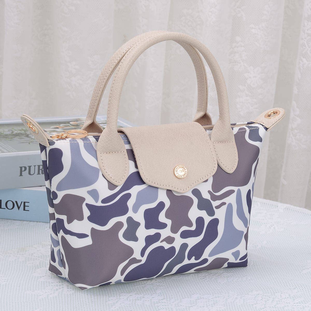 Handbag with camouflage pattern and beige handle on a light background
